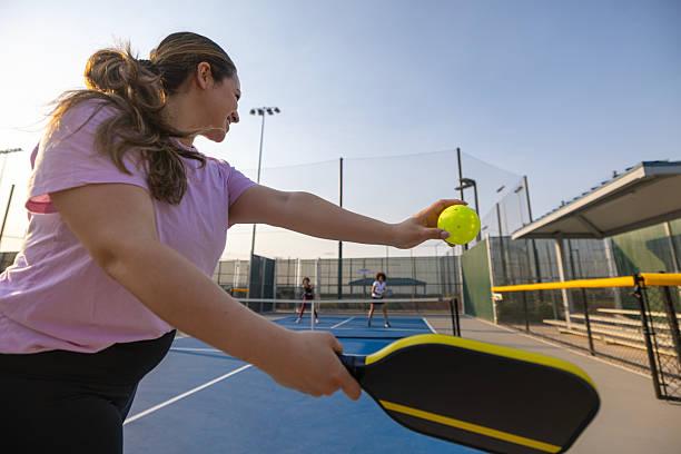 Female player hitting a forehand shot with a pro pickleball paddle on a blue court