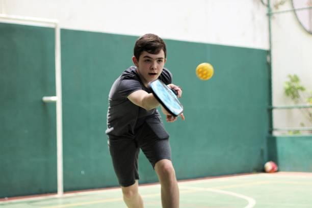 Teenage player executing a forehand drive with a performance pickleball paddle, demonstrating the need for responsive gear for competitive intermediate youth players.