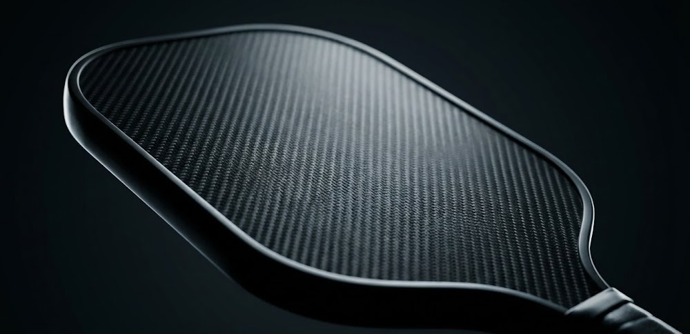 Seven textured pickleball paddles fanned out, displaying a variety of edge guard colors including red, white, blue, and black.
