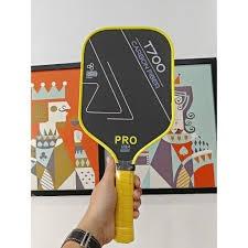 Hand holding a pro-level T700 carbon fiber pickleball paddle showing the textured surface detail
