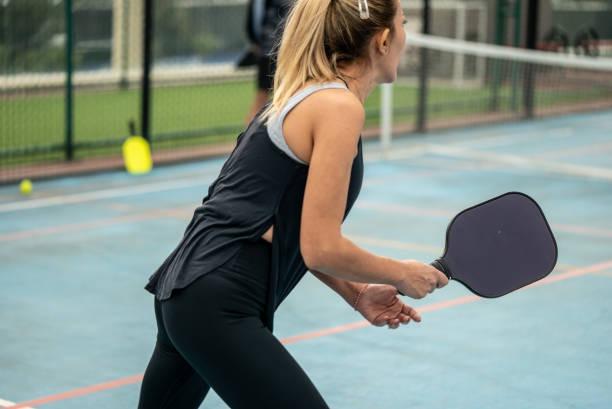Male player holding a green ball and a black paddle, feeling the swing weight distribution of the equipment before play