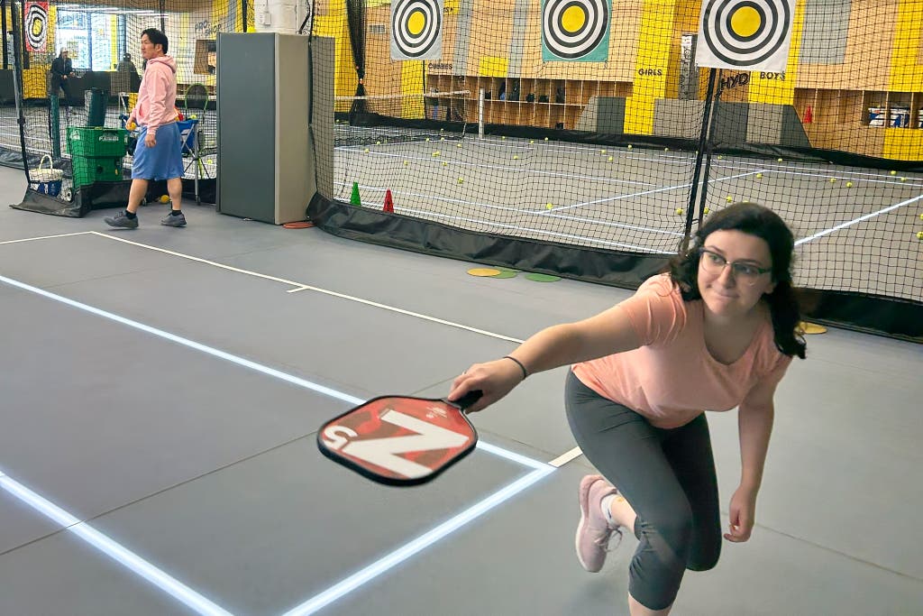 Woman plays pickleball indoors, ready to hit the ball with her modern pickleball paddles.