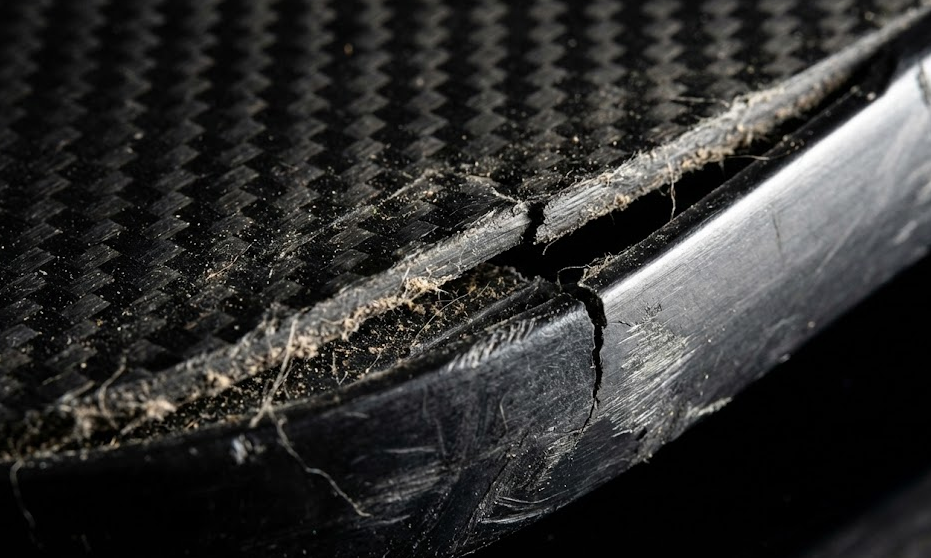Damaged pickleball paddles edge with carbon fiber texture.