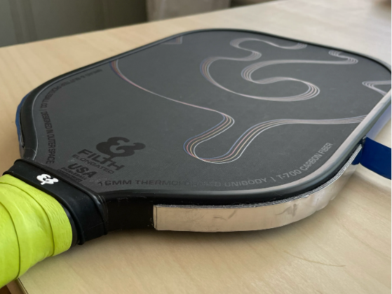 Close-up of a modern, dark grey Pickleball Paddles with green grip.