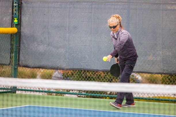 Woman serving with pickleball paddles on court