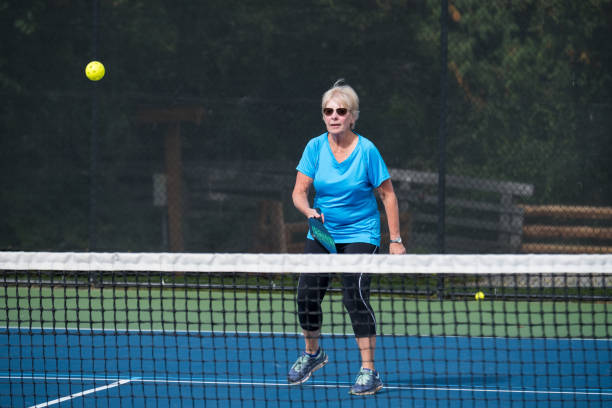 Woman playing pickleball with pickleball paddles and ball