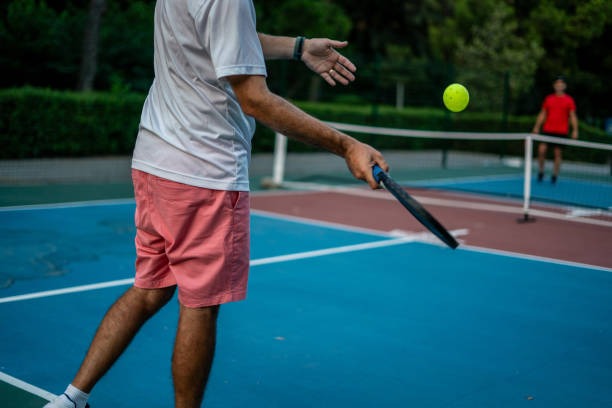 Man playing pickleball with pickleball paddles on a court.