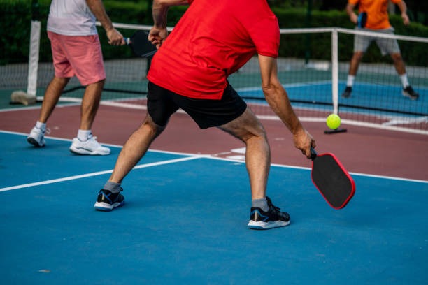 People actively playing pickleball outdoors with various pickleball paddles on a vibrant court.