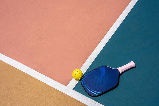 Blue pickleball paddle and ball on colorful court.