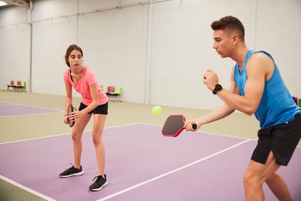 Young people playing pickleball with pickleball paddles.
